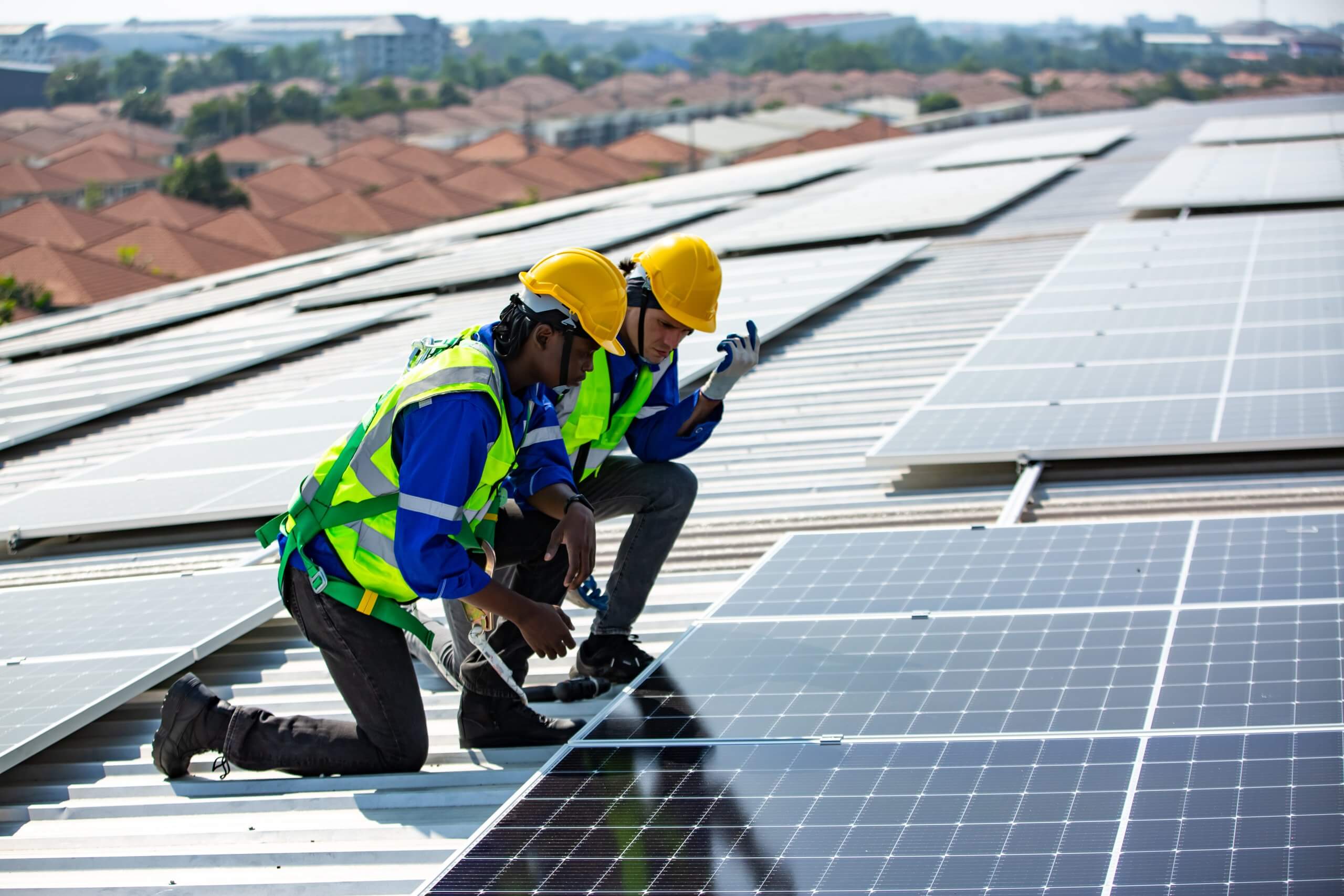 Solar panel installer installing solar panels on roof of warehouse