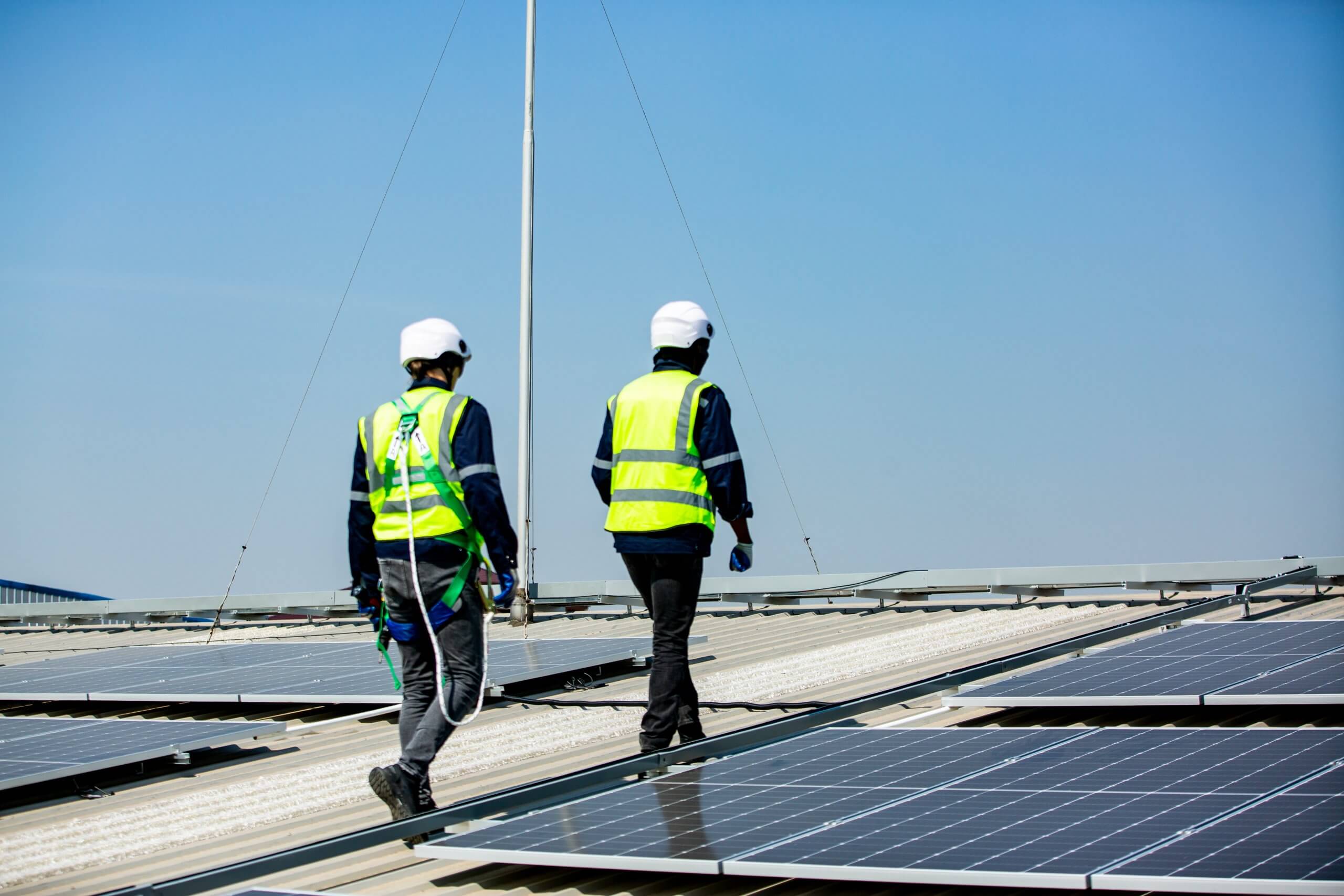 Solar panel installer installing solar panels on roof of warehouse