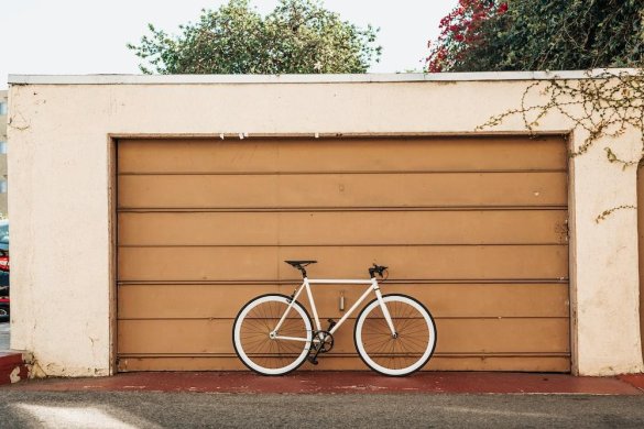 bicicleta blanca apoyada en una persiana enrollable marrón