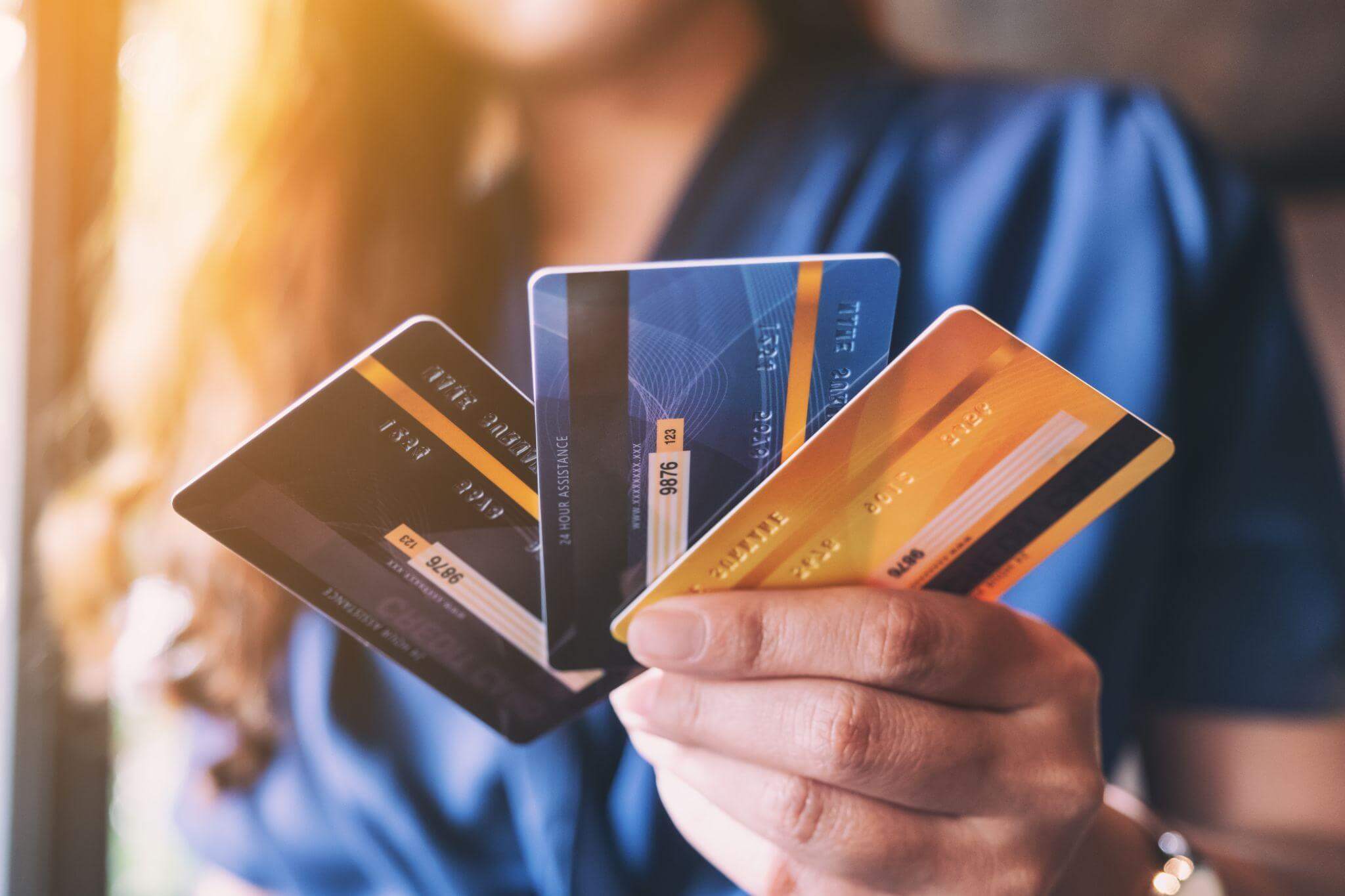 A close-up of a woman's hand holding and displaying multiple credit cards.